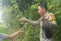 Bripka Andi Rusman tengah membentangkan kabel listrik ke rumah warga. (ist)