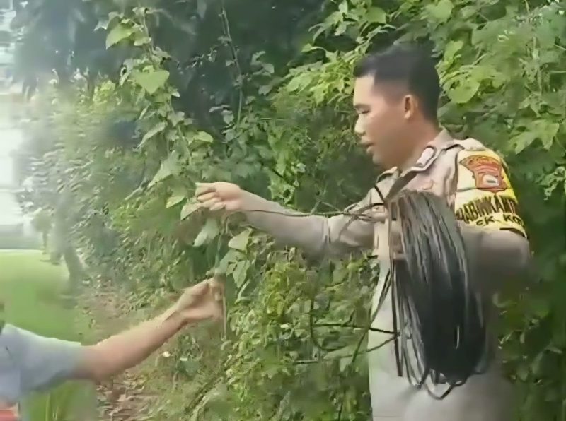 Bripka Andi Rusman tengah membentangkan kabel listrik ke rumah warga. (ist)