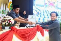 Ketua BK DPRD Kaltim Subandi, menyerahkan pengesahan kode etik dan tata beracara kepada Ketua DPRD Kaltim, Hasanudin Mas'ud. (Foto/Hms)